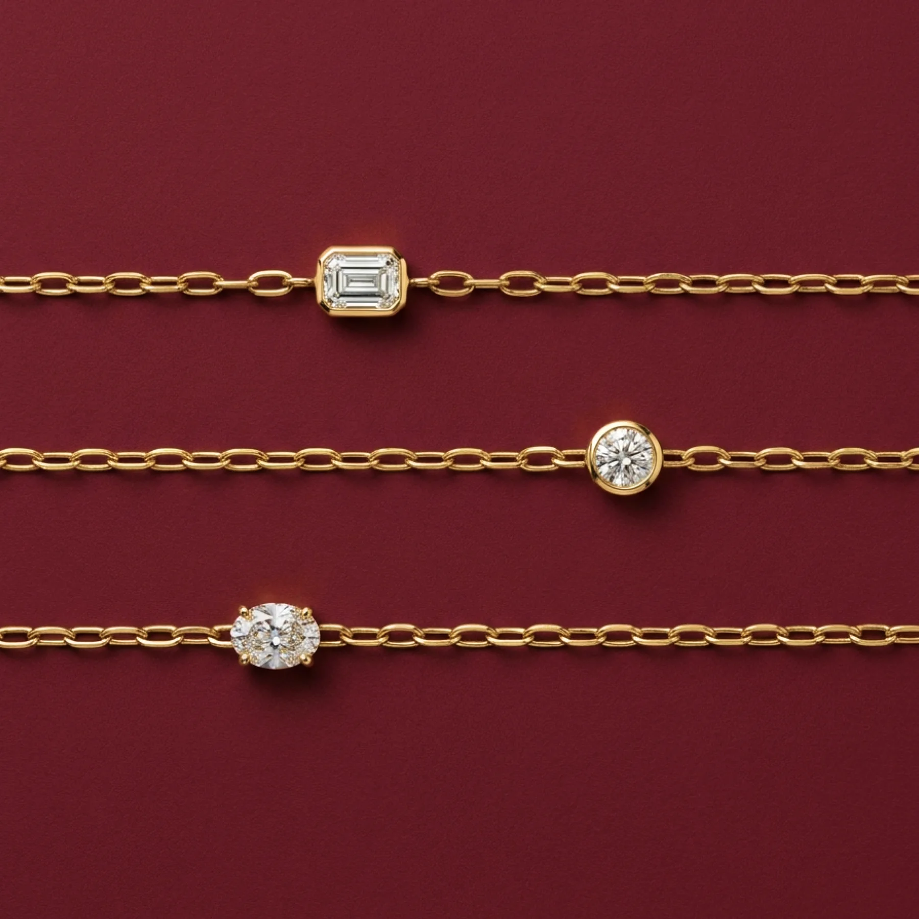 Three fine diamond bracelets on burgundy velvet.