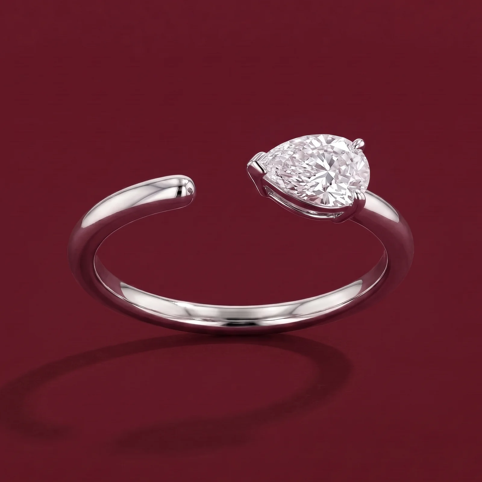A pear diamond companion ring on burgundy velvet.