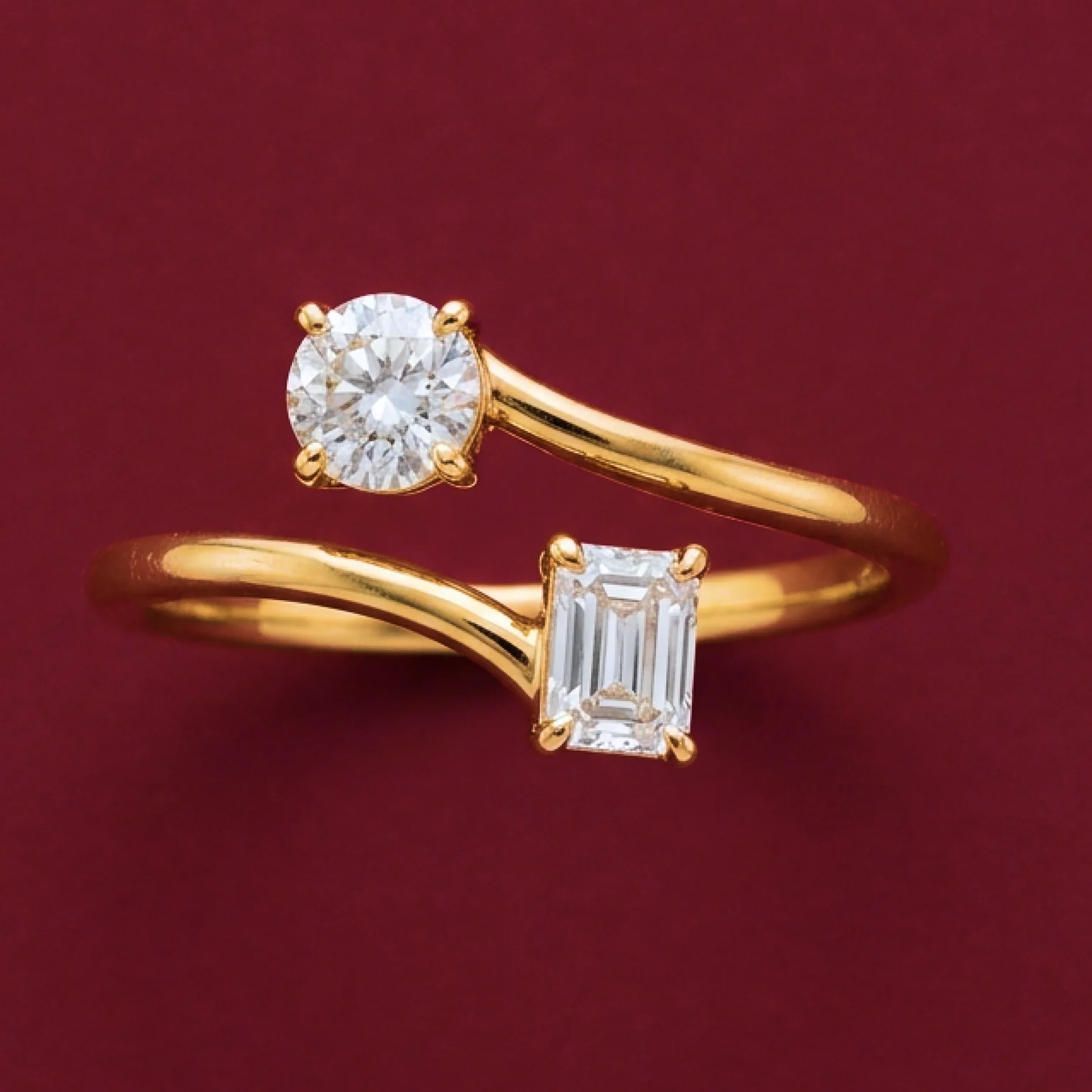 A two-stone warm-gold love ring on burgundy velvet.